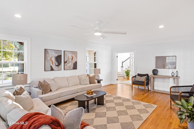 living area featuring light wood finished floors, stairs, ornamental molding, and a ceiling fan