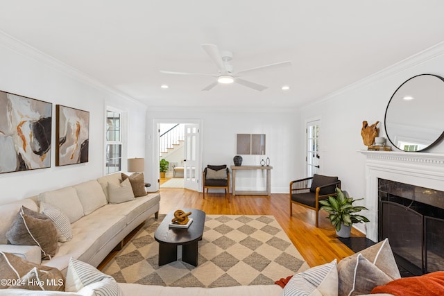 living room with light wood finished floors, stairs, a premium fireplace, and crown molding