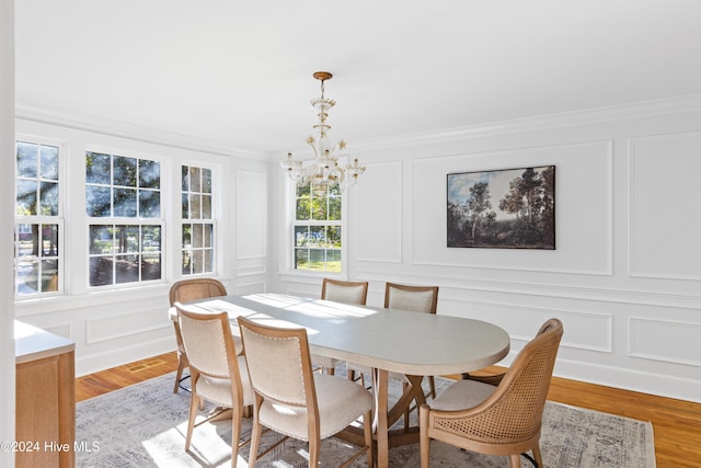 dining room with a chandelier, a decorative wall, and light wood finished floors