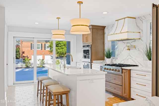 kitchen with decorative backsplash, custom range hood, light stone counters, appliances with stainless steel finishes, and a sink