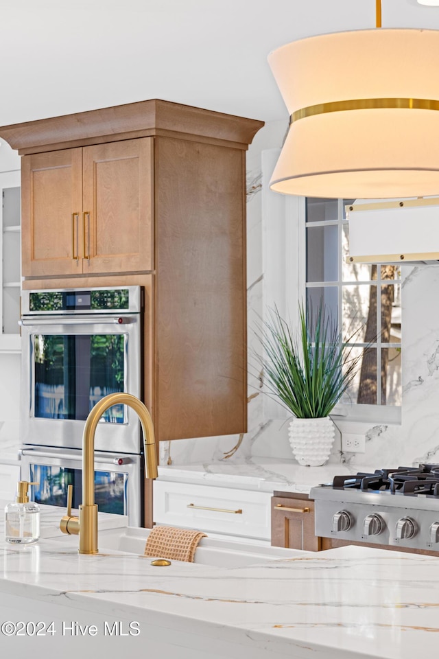 interior details featuring double oven, backsplash, and light stone countertops