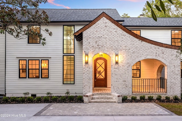 view of front facade featuring a shingled roof and brick siding