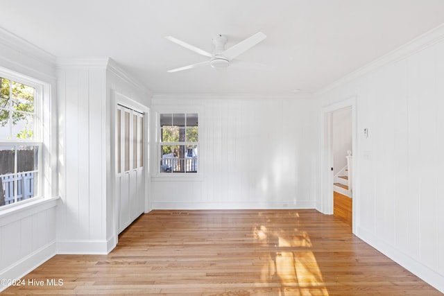 spare room featuring ornamental molding, light wood-type flooring, a healthy amount of sunlight, and a ceiling fan