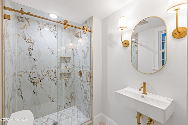 bathroom featuring a marble finish shower, baseboards, visible vents, toilet, and a sink