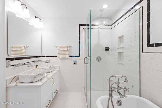 bathroom featuring tile walls, a soaking tub, wainscoting, a shower stall, and vanity