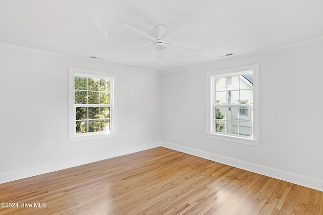 spare room featuring crown molding, light wood finished floors, visible vents, a ceiling fan, and baseboards