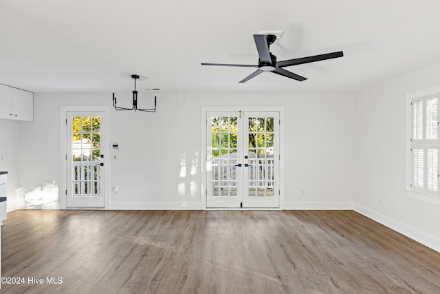 unfurnished dining area featuring french doors, plenty of natural light, baseboards, and wood finished floors