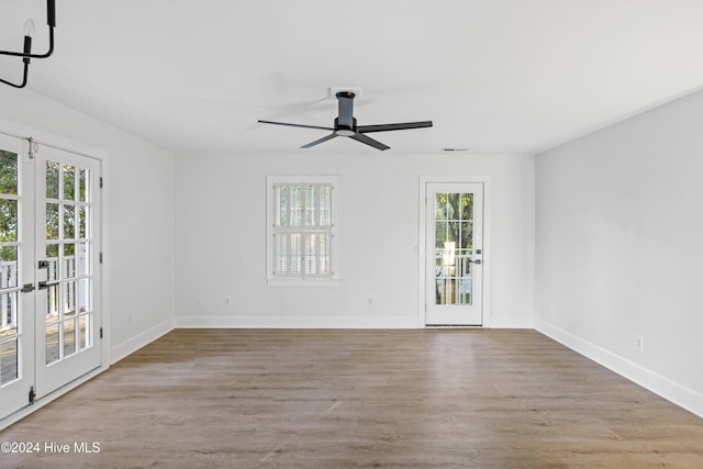 unfurnished room with ceiling fan, wood finished floors, visible vents, and baseboards