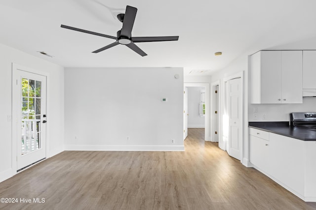 kitchen with dark countertops, visible vents, light wood-style flooring, white cabinets, and stainless steel range with electric stovetop