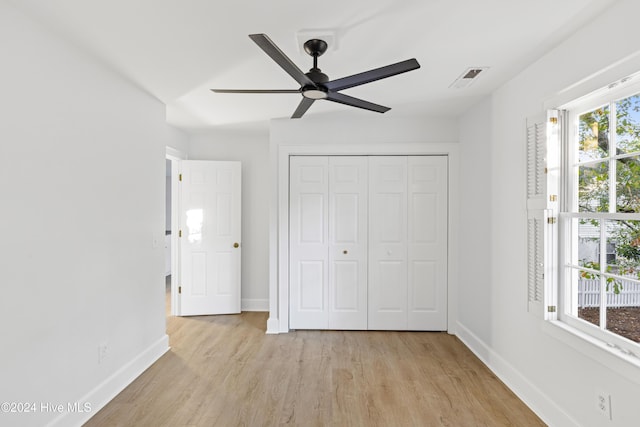 unfurnished bedroom with light wood finished floors, baseboards, visible vents, a ceiling fan, and a closet