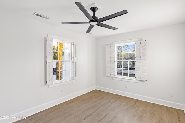 empty room with visible vents, ceiling fan, baseboards, and wood finished floors