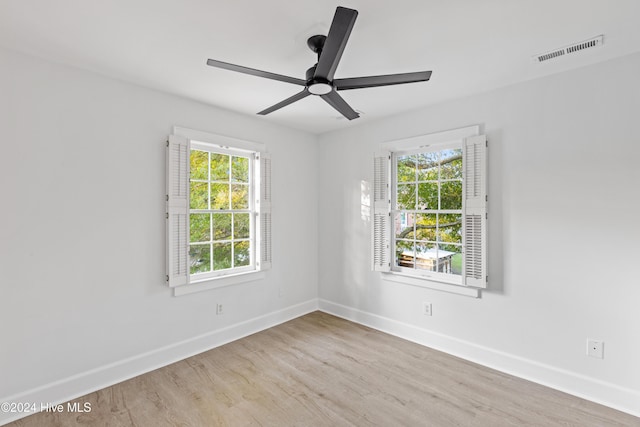 empty room with a ceiling fan, wood finished floors, visible vents, and baseboards