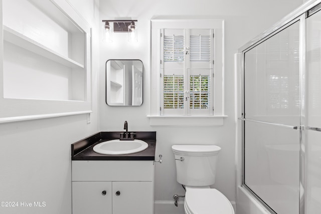 full bathroom with a shower with shower door, vanity, and toilet