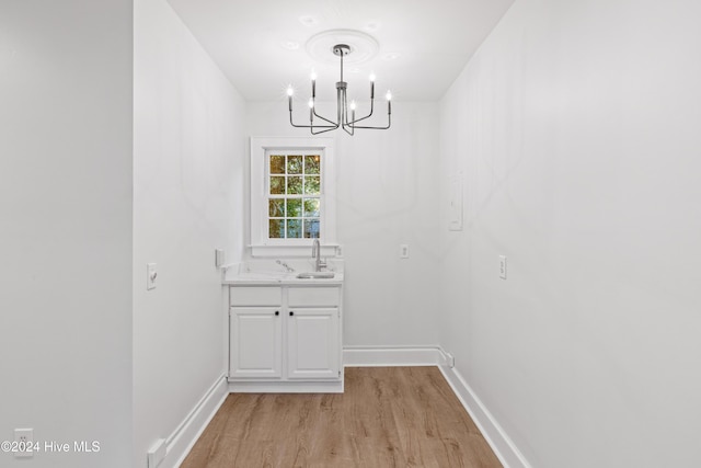 interior space featuring a sink, a notable chandelier, light wood finished floors, and baseboards