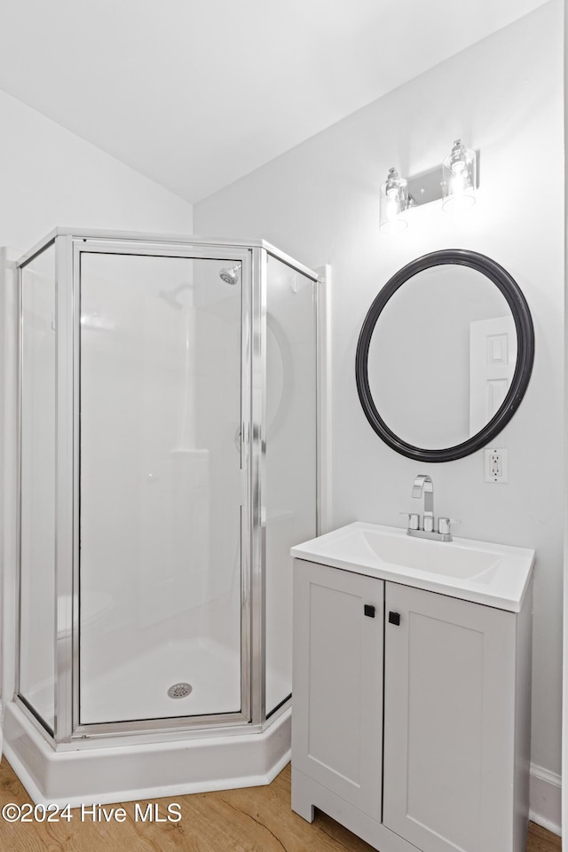 bathroom with lofted ceiling, a stall shower, wood finished floors, and vanity