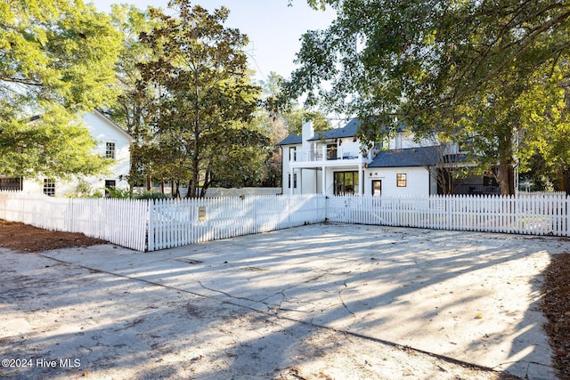 view of front facade with a balcony, a fenced front yard, and a chimney