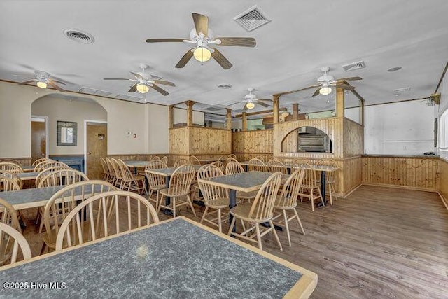 dining space featuring visible vents, a ceiling fan, and a wainscoted wall