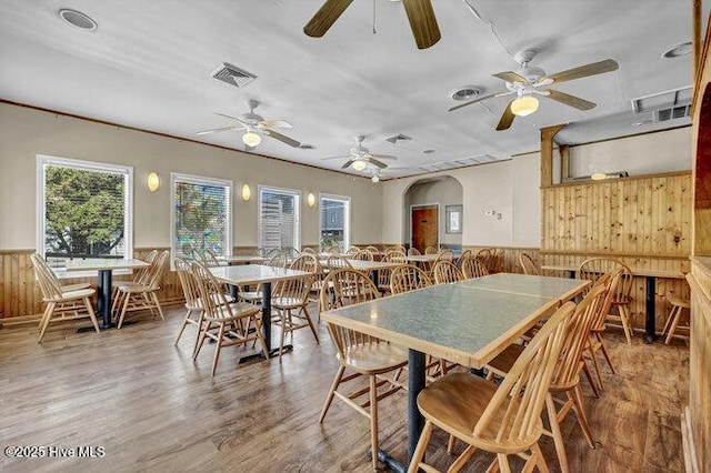 dining area featuring a ceiling fan, visible vents, wood walls, and wainscoting