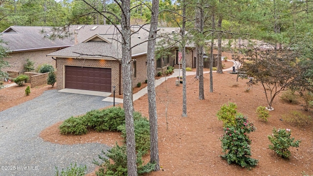 view of front of house featuring gravel driveway, roof with shingles, and brick siding