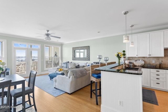 interior space featuring white cabinets, a sink, light wood finished floors, and a breakfast bar area