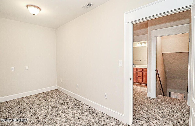 carpeted spare room featuring baseboards and visible vents