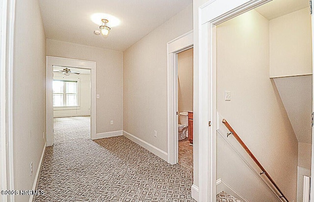 hallway with carpet floors, baseboards, and an upstairs landing