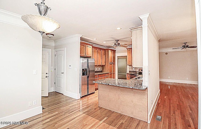 kitchen with light wood finished floors, ornamental molding, brown cabinetry, a ceiling fan, and stainless steel fridge