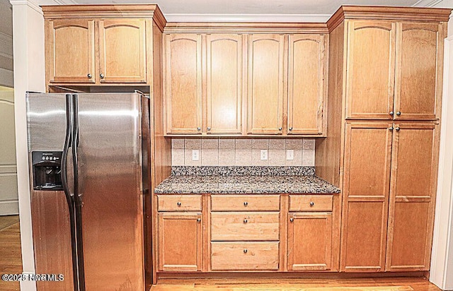 kitchen featuring dark stone counters, light wood finished floors, backsplash, and stainless steel fridge