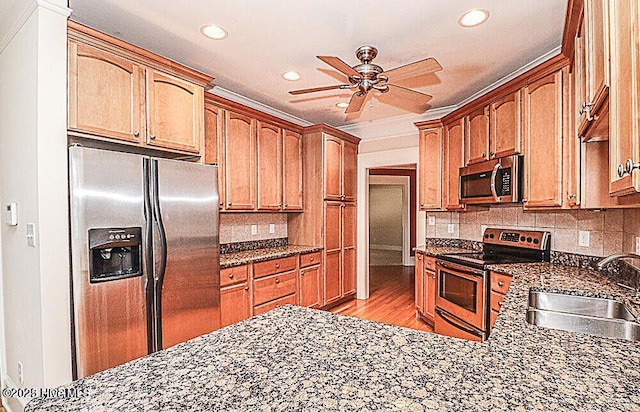 kitchen with backsplash, appliances with stainless steel finishes, dark stone counters, and a sink