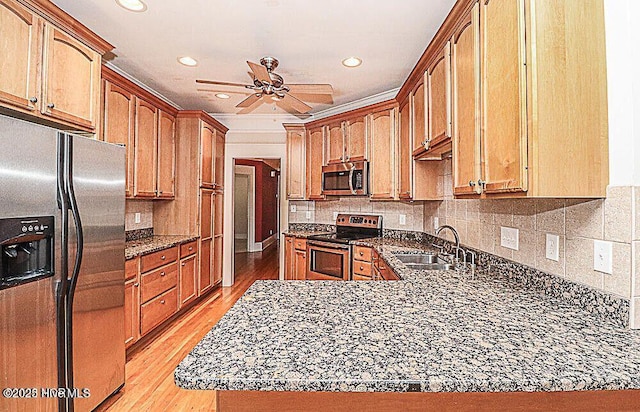 kitchen with ceiling fan, appliances with stainless steel finishes, dark stone countertops, light wood-type flooring, and a sink