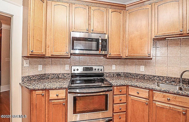 kitchen with dark stone counters, appliances with stainless steel finishes, backsplash, and a sink