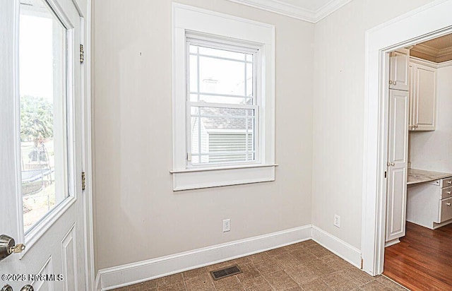 interior space with baseboards, dark floors, visible vents, and crown molding