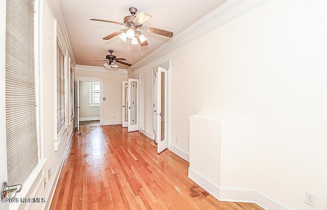 corridor with light wood-type flooring, crown molding, and baseboards