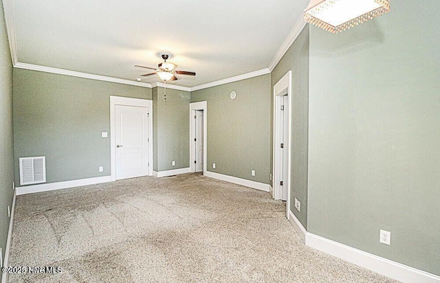 carpeted spare room featuring visible vents, crown molding, baseboards, and ceiling fan