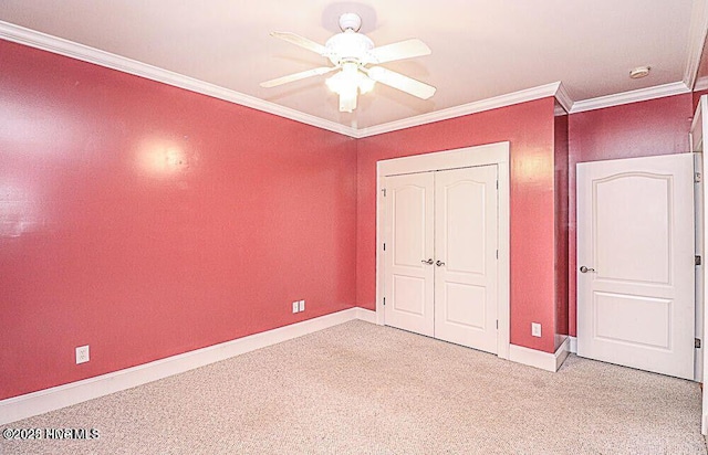 unfurnished bedroom with crown molding, a closet, a ceiling fan, light carpet, and baseboards