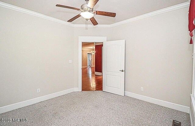 unfurnished room with carpet, visible vents, crown molding, and baseboards