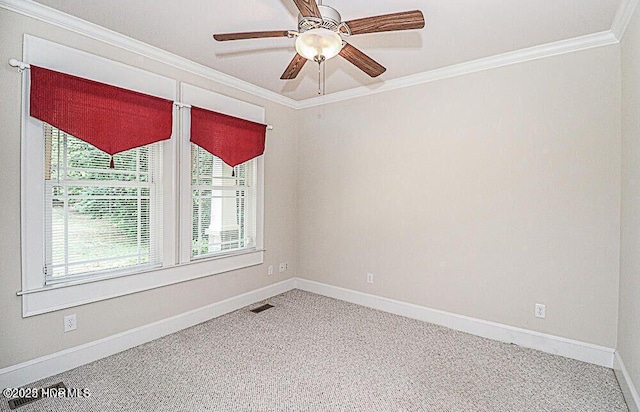 empty room featuring a ceiling fan, baseboards, visible vents, carpet, and crown molding