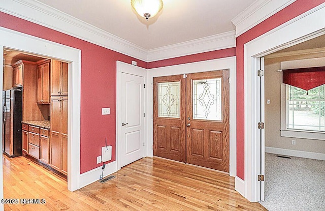 entryway featuring baseboards, light wood-style floors, visible vents, and crown molding