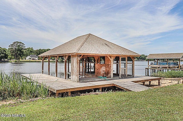 dock area featuring a water view, a lawn, and boat lift