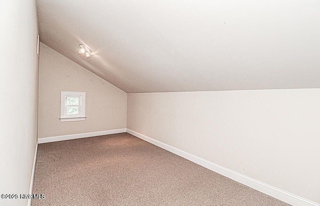 additional living space with carpet, vaulted ceiling, and baseboards