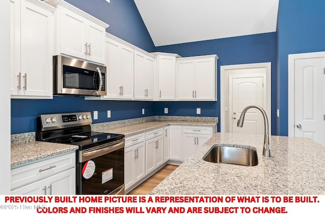 kitchen featuring lofted ceiling, a sink, stainless steel appliances, white cabinets, and light wood-style floors