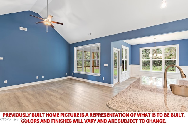 unfurnished living room with light wood-type flooring, ceiling fan with notable chandelier, visible vents, and a sink