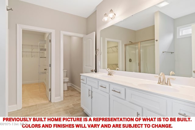 bathroom with double vanity, a stall shower, toilet, and a sink