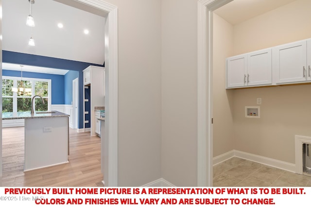 laundry area with a chandelier, a wainscoted wall, washer hookup, cabinet space, and a sink