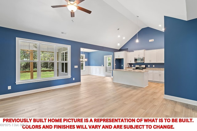 kitchen with open floor plan, ceiling fan with notable chandelier, appliances with stainless steel finishes, white cabinets, and a sink