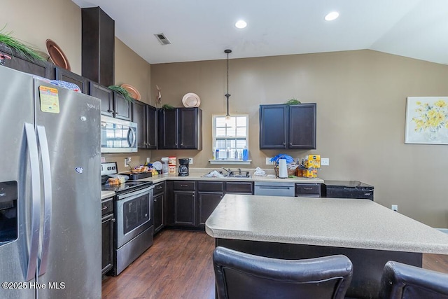 kitchen with dark wood-style flooring, visible vents, vaulted ceiling, light countertops, and appliances with stainless steel finishes