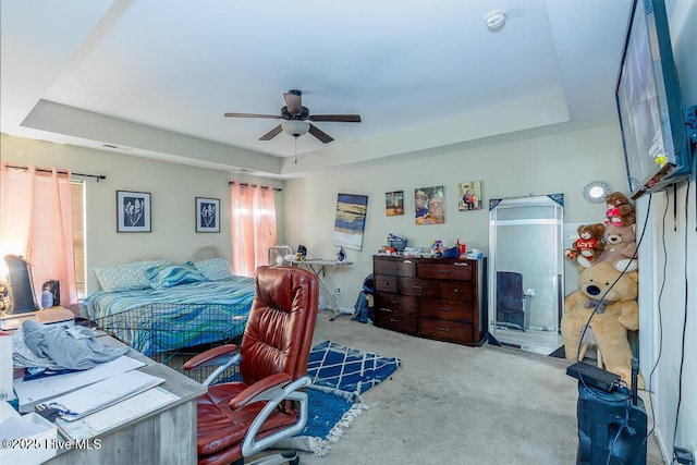 carpeted bedroom with a barn door, a tray ceiling, and ceiling fan