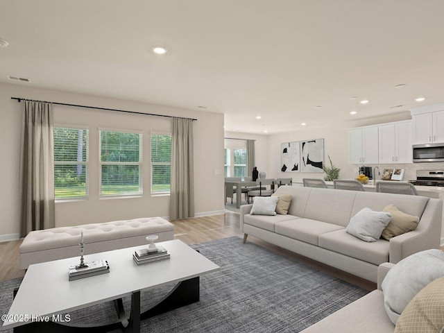 living room featuring baseboards, light wood finished floors, visible vents, and recessed lighting