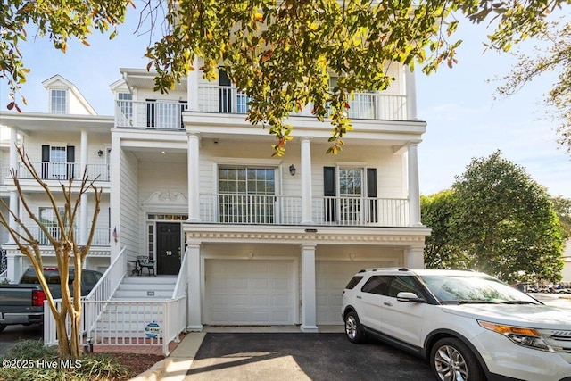 view of front facade featuring an attached garage, driveway, and a balcony