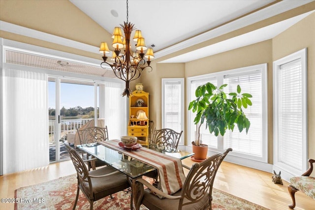 dining room featuring vaulted ceiling, a wealth of natural light, a chandelier, and wood finished floors